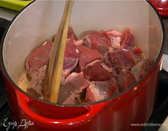 Разогреть в тяжелой кастрюле оливковое масло и на сильном огне обжаривать мясо со всех сторон до появления золотистой корочки.