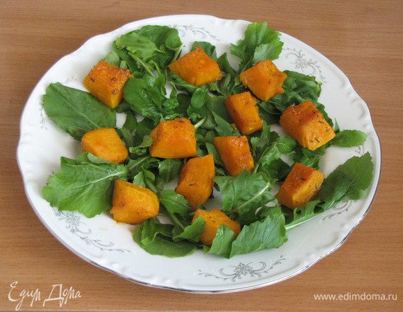 Помоем и посушим руколу. Выложим на блюда, добавим кубики запеченной тыквы.