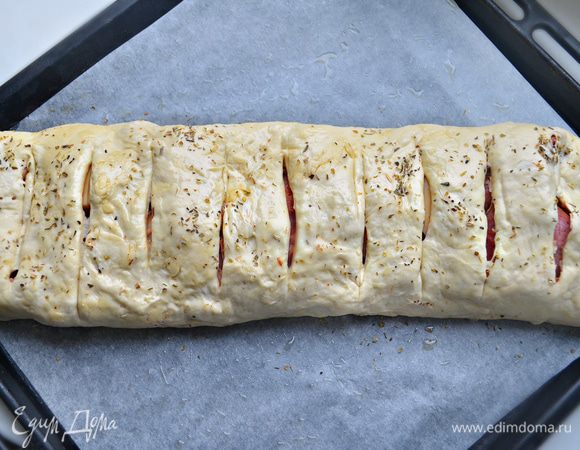 Аккуратно сверните рулет и уложите швом вниз на противень, покрытый пекарской бумагой и смазанный оливковым маслом. Посыпьте сушеным орегано и сделайте на рулете с помощью острого ножа поперечные надрезы.