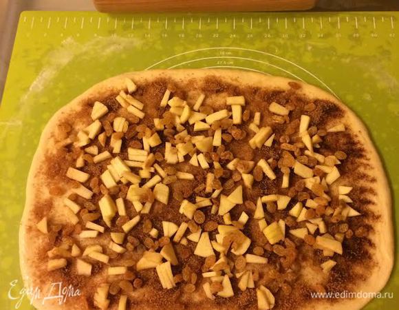 Сахар смешать с корицей. Яблоки мелко нарезать. Тесто раскатать, смазать растопленным сливочным маслом, посыпать сахаром с корицей. Сверху выложить яблоки и изюм.