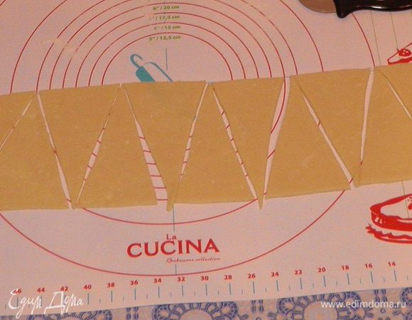 Раскатайте тесто в пласт толщиной примерно 0,5 см. Тесто разделите на треугольники.