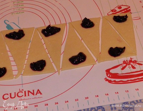 На основание треугольника положите густое варенье или повидло. Заверните рогалик от широкой части треугольника к узкой.