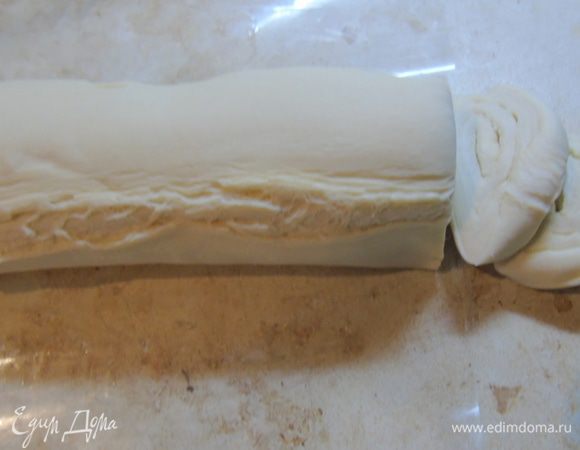 Слоеное тесто нужно разморозить, свернуть  рулетом и нарезать кусочками.