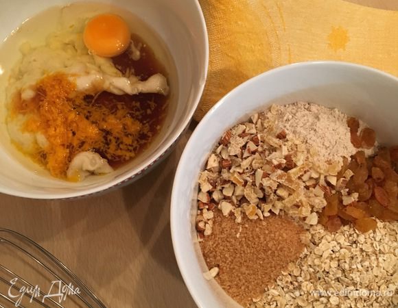 Берем две миски. В одной смешиваем все сухие ингредиенты: муку, овсяные хлопья, разрыхлитель, сахар, специи, изюм, измельченные орехи и имбирные цукаты. Во второй миске размять банан вилкой (или пюрировать блендером), добавить к нему яйцо, масло, мед и цедру. Взбить все венчиком.