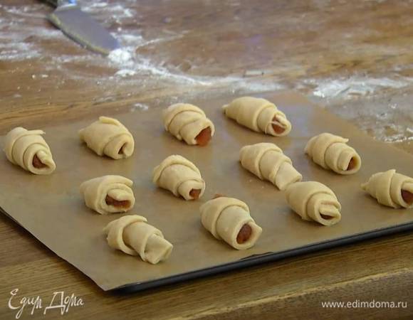 Второй круг разрезать на 12 треугольников-секторов, на широкую часть каждого выложить по 1 ч. ложке яблочного повидла и скрутить рогалик, затем выложить на противень, выстеленный бумагой для выпечки, и дать им немного подойти.