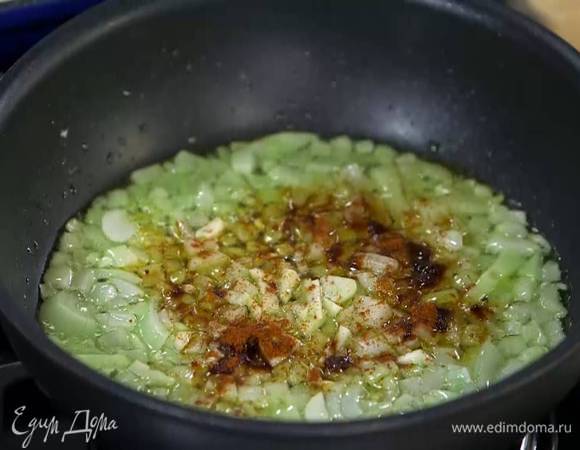 Чеснок почистить, мелко порезать, добавить к луку и перемешать, затем всыпать паприку и все обжарить.