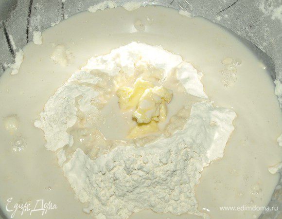 В муке сделать сначала горку, а потом лунку и добавить туда размягченное сливочное масло. Влить молоко с водой и дрожжами.
