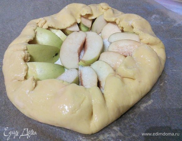 С помощью бумаги прикрыть края галеты, слегка придавливая тесто. Смазать желтком. На айву разложить кусочки сливочного масла. 