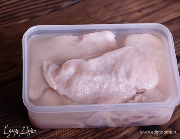 Замаринуем куриное филе. Для этого помоем его, разрежем вдоль пополам (чтобы получились стейки примерно одинаковой толщины), уложим в контейнер. Из лимона выжмем сок, смешаем примерно с 1,5 стаканами чистой холодной воды и зальем этим маринадом куриные филе. Контейнер закрываем и оставляем мариноваться в холодильнике минимум на 8 часов.