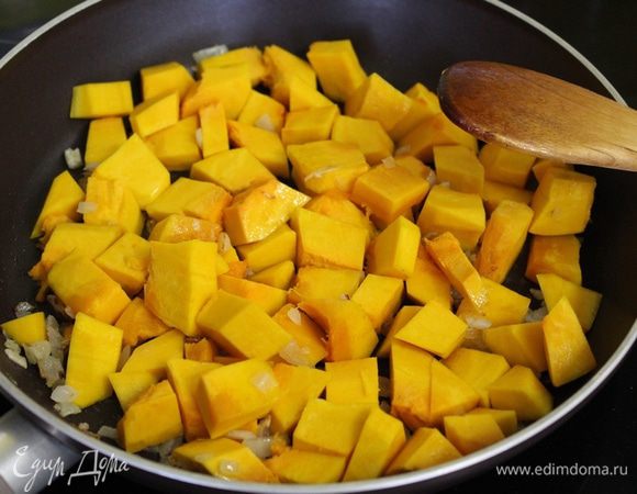 Лук и чеснок пассировать в небольшом количестве масла. Тыкву порезать на кусочки, добавить в сковороду.