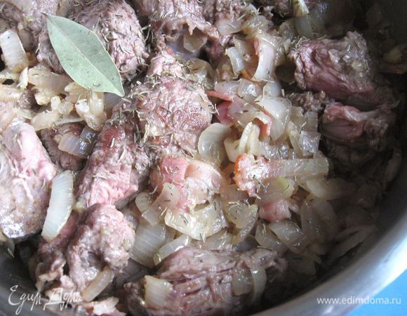 Переложить мясо из сковороды в теплоемкую кастрюлю с толстым дном. Посолить, поперчить, добавить тимьян, лавровый лист.
