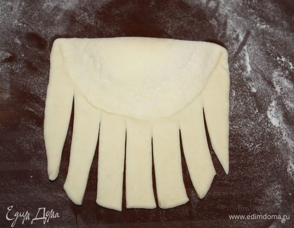 Загибаем один край теста до середины, а оставшееся тесто разрезаем на полоски, как показано на фото.