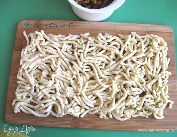 Духовку разогреть до 180°С. Вынуть тесто из холодильника, пропустить через мясорубку. Уложить прямоугольным пластом на дощечку.