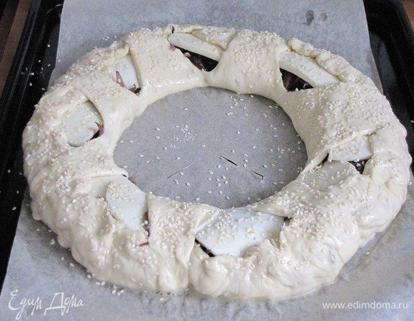 Подвернуть края пирога и накрыть их треугольниками из центра. Смазать пирог слегка взбитым яйцом и посыпать по желанию кунжутом. Поставить в разогретую до 180°С духовку и выпекать минут 30 или до зарумянивания.