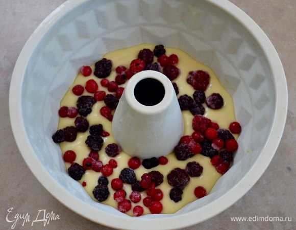 Половиной теста заполнить круглую форму для кексов (с тубой в центре) 20 см в диаметре. Поверх теста выложить половину от количества ягод. Выложить оставшееся тесто и сверху присыпать ягодами. 
