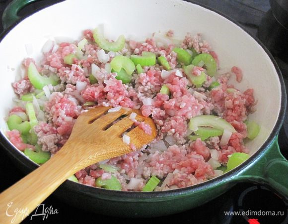 В большой сковороде разогреть растительное масло, добавить лук, сельдерей и фарш. Жарить, разбивая фарш на мелкие крошки, минут 10.
