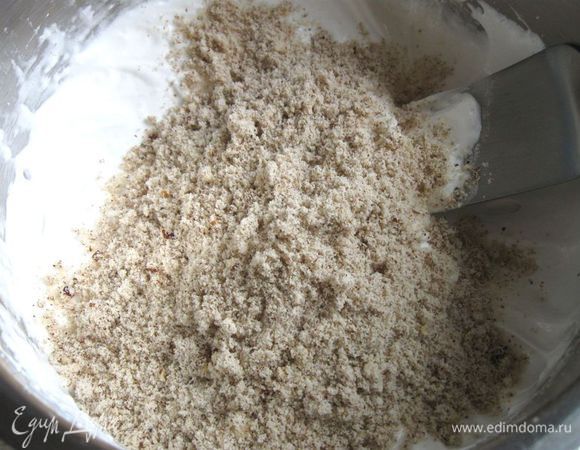 Затем добавить орехи в три порции. Это первая порция. Несколькими легкими движениями лопаточкой аккуратно перемешать.