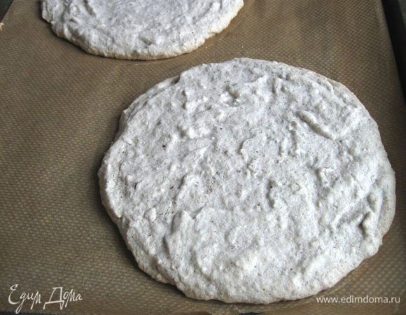 Вынуть коржи из духовки.  Дать немного постоять. Аккуратно, коржи хрупкие, вместе с бумагой снять с противня.  Подвинуть немного корж с бумагой на край стола таким образом, чтобы он немного заходил за плоскость стола, и постепенно передвигая корж, загибая бумагу перпендикулярно поверхности стола, снять бумагу. Как подставочку для перемещенного со стола коржа я использую кухонную доску. Дать постоять до полного охлаждения.