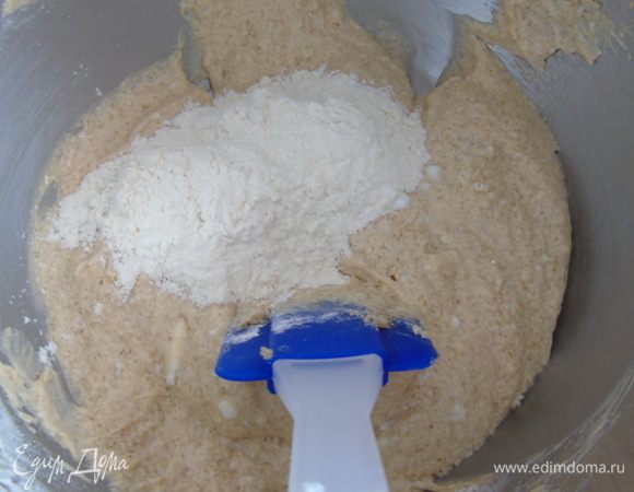 Добавьте 1/3 часть муки в тесто и уже перемешивайте лопаткой, затем половину кефира, опять 1/3 муки и остальной кефир.