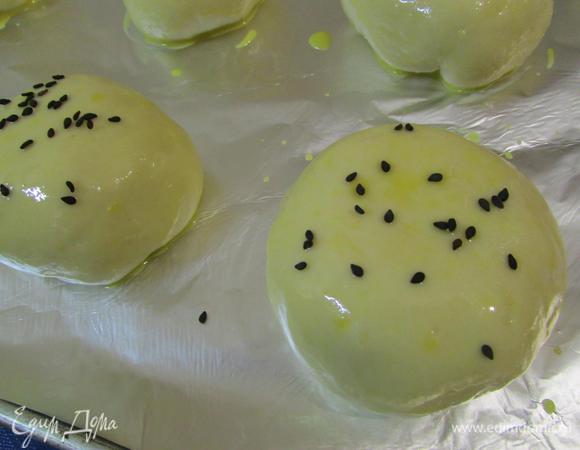 Затем булочки присыпать кунжутом или натертым на мелкой терке пармезаном. Булочки отправить в разогретую духовку до 180°С. Выпекать 20 минут. Готовые булочки извлечь из духовки. Перенести булочки вместе с пекарской бумагой на решетку. Дать остыть.