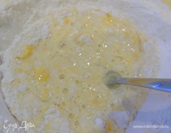 Вливаем теплое молоко, воду, яйца и ложкой замешиваем.