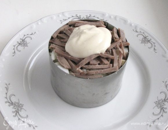 Далее выложить слои в следующем порядке: красный лук, морковь, огурцы, яйца и снова язык. Слои слегка прижимать вилкой, подсаливать и прослаивать соусом.