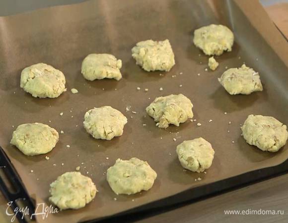 Руками сформировать из теста небольшие, плотные лепешки и выложить на противень, выстеленный бумагой для выпечки.
