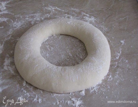Растягивая тесто, на весу сформировать кольцо. Посыпать сверху мукой, накрыть полотенцем и оставить на 30 минут.