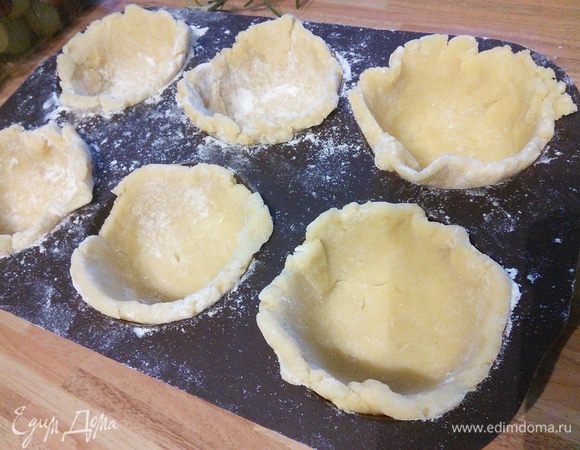 Форму для маффинов выложить бумажными стаканчиками (у меня силиконовая, поэтому я ими не пользуюсь). Большую часть теста раскатать кружочками и выложить в формы в виде «чашечек», причем бортики должны быть чуть выше самих формочек.