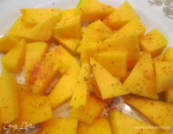 Тыкву, очищенную от кожицы, нарезаем кубиками и выкладываем на противень на пекарской бумаге или фольге. 
Поливаем маслом, посыпаем паприкой, солью и перцем.
