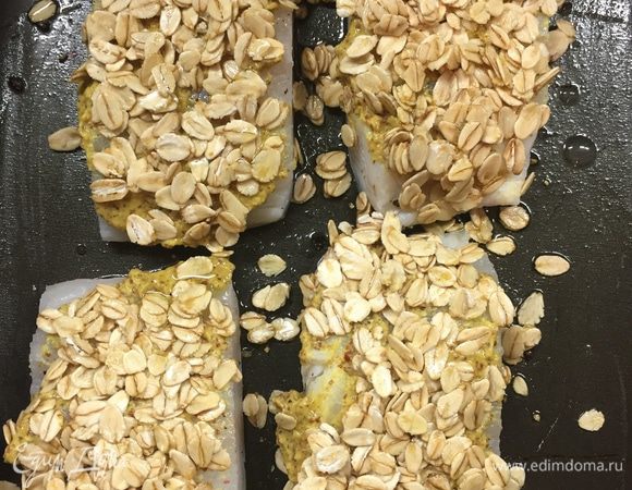 В миске смешать овсяные хлопья и оливковое масло. Я привела пропорции на глаз. Хлопья должны быть просто слегка, но равномерно смазаны маслом. Только обязательно берите обычные хлопья, не instant, которые варятся не меньше 15 минут.
Положите на каждую филе по горсточке и ласково прихлопните.
Валяющиеся на противне хлопья вообще лучше убрать — они будут гореть.
Сверху сбрызните еще оливковым маслом, если кажется, что остались хлопья без покрытия.
