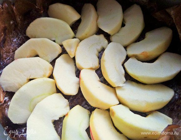 Съёмную форму (диаметр 21 см) застелить смазанным сливочным маслом пергаментом и на дно уложить дольки яблок.