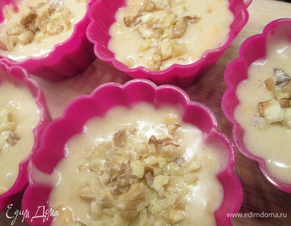 Соединяем обе смеси — мучную и яичную. В формочки укладываем пекарскую бумагу (в силиконовые не надо) и выливаем в них тесто, не доливая немного до краев. Сверху посыпаем орешками и слегка утапливаем их.