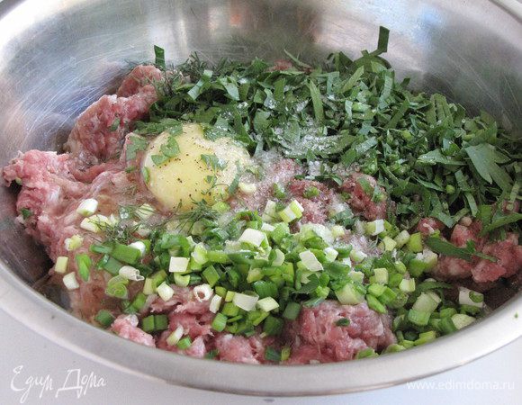 В фарш добавить специи, яйцо, нашинкованную зелень. Вымесить фарш до однородной массы.