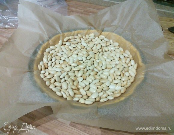 Разогреть духовку до 180С°. На тесто выложить лист пергаментной бумаги и разложить груз (фасоль или горох), слегка придавить и выпекать 20 минут. Затем достать из духовки и чуть охладить. 
