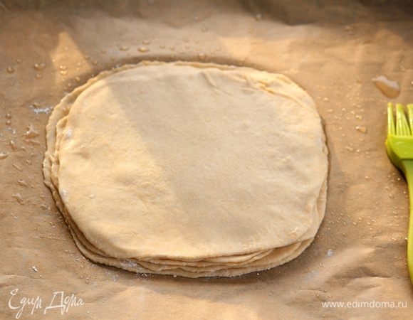 Теперь,  необходимо раскатать каждый шарик от первого деления в круг, раскладывая на смазанном пергаменте (уже на противне). Каждый слой промазываем растительным маслом, кроме верхнего.