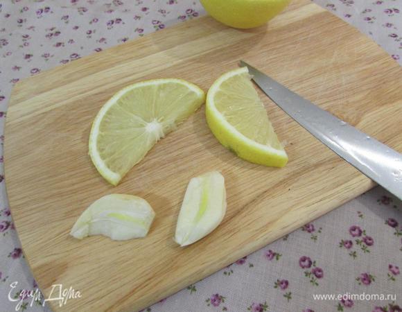 Зубчик чеснока почистить и разрезать вдоль на две пластинки. Ломтик лимона разрезать пополам.