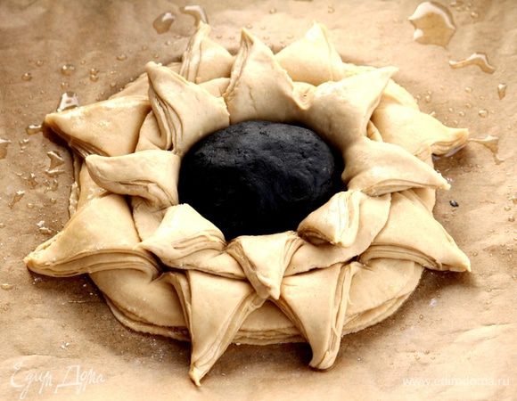 В образовавшееся отверстие по размеру размещаем шарик из черного теста. Наш цветок смазываем яйцом и посыпаем кунжутом. Выпекаем первые 10 минут при температуре 200°С, а затем 25 — 30 минут при 180°С.