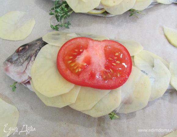 Сверху картофеля на рыбу выложить по ломтику помидоров.