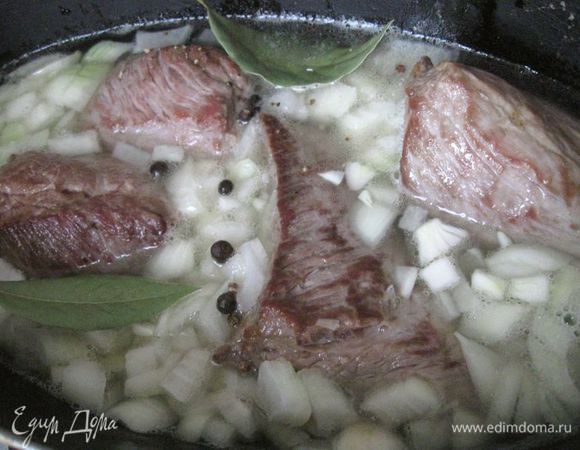 Переложить в жаровню, добавить душистый перец горошком, лавровый лист, мелко нашинкованный репчатый лук (лука должно быть много), залить кипятком таким образом, чтобы мясо было покрыто не полностью. Добавить оставшуюся соль. В это блюдо добавляю несколько зубчиков чеснока, пропущенных через пресс. Накрыть крышкой и тушить 1 час.