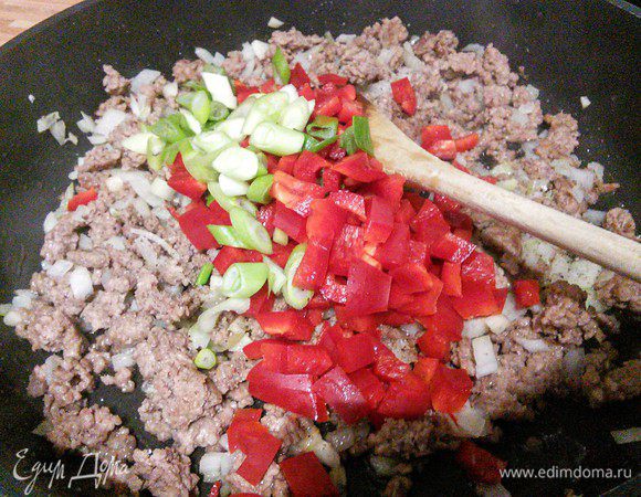 Добавить нарезанный мелким кубиком перец и кружочком зеленый лук (небольшое количество лука оставьте для подачи), обжарить вместе в течение нескольких минут. 