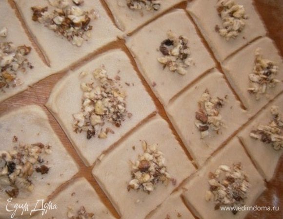 Разрезаем тесто на квадратики примерно 7х7 см и в середину каждого кладем орешки.