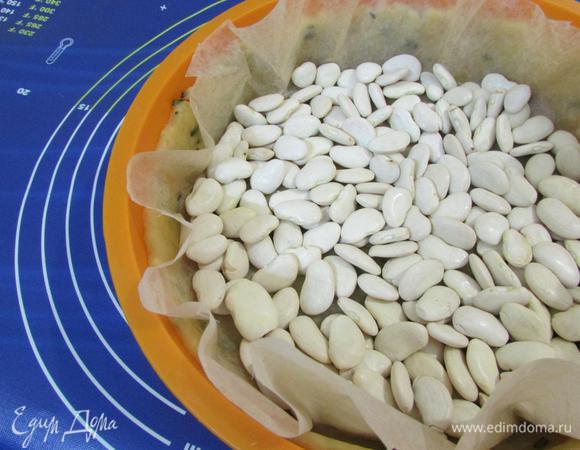 Сверху теста положить лист пекарской бумаги, насыпьте фасоль. И отправьте в разогретую духовку (180°С). Выпекать 20 минут. Затем снять бумагу и груз.