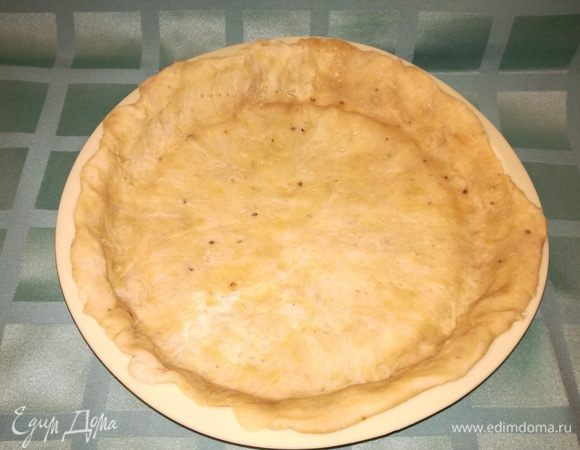 Достать из холодильника тесто и раскатать его до 0,6 — 0,8 см. Процесс этот довольно трудоемкий, т.к. тесто плотное, но довольно хрупкое, а масло норовит растаять и «прилипнуть» к скалке. Облегчить процесс раскатывания теста можно, положив его между двумя листами пергаментной бумаги и/или привлечь к процессу мужскую силу.
С таким трудом сформированную круглую лепешку помещаем в форму. У меня силиконовая Ø24 см. Хорошо формируем бортики пирога.
Сделать на дне и боках проколы вилкой.
Разогреть до 190°С духовку и выпекать основу для пирога 10 мин.
Дать остыть 20 мин. 