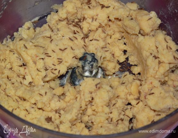 Добавить разрыхлитель, черный перец, травы, сливки и муку. Тщательно перемешать. Добавить тмин и замесить тесто. Солить не нужно, т. к. сыр уже содержит достаточно соли.