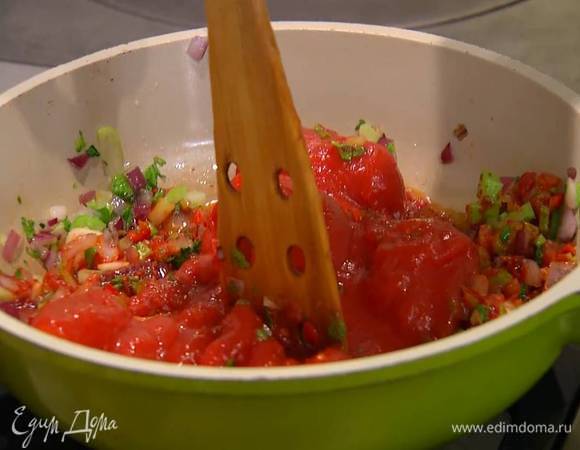Перец чили мелко порубить и добавить к овощам, затем выложить в сковороду консервированные помидоры, измельчить их лопаткой, все посолить и прогреть на маленьком огне.