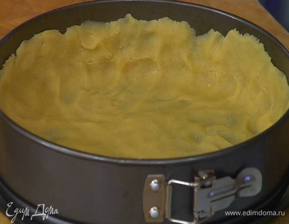 Равномерно распределить тесто по дну и стенкам разъемной формы, так чтобы получился тонкий корж с высокими бортиками, часто наколоть вилкой и отправить в разогретую духовку.