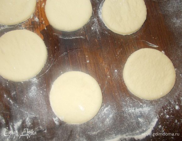 Вырезать кружочки (стаканом или специальным кругом для пирожных) диаметром 5 — 6 см. Собрать обрезки в ком и опять раскатать в пласт. Вырезать кружочки. И так все тесто