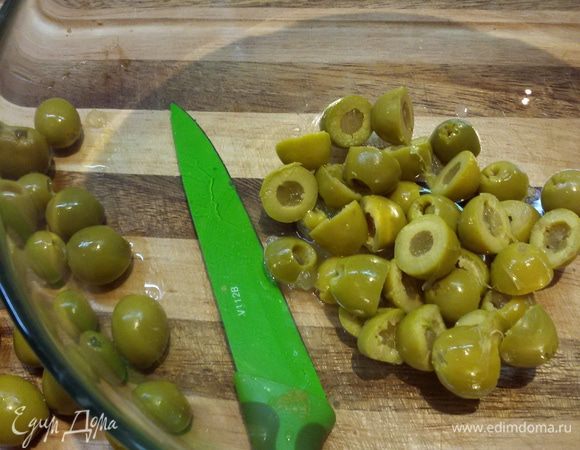 Оливки разрезать на половинки.