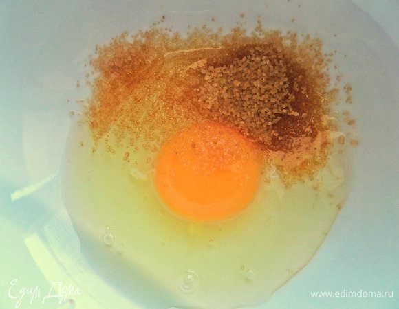 В небольшую миску вбить яйцо, всыпать коричневый сахар.